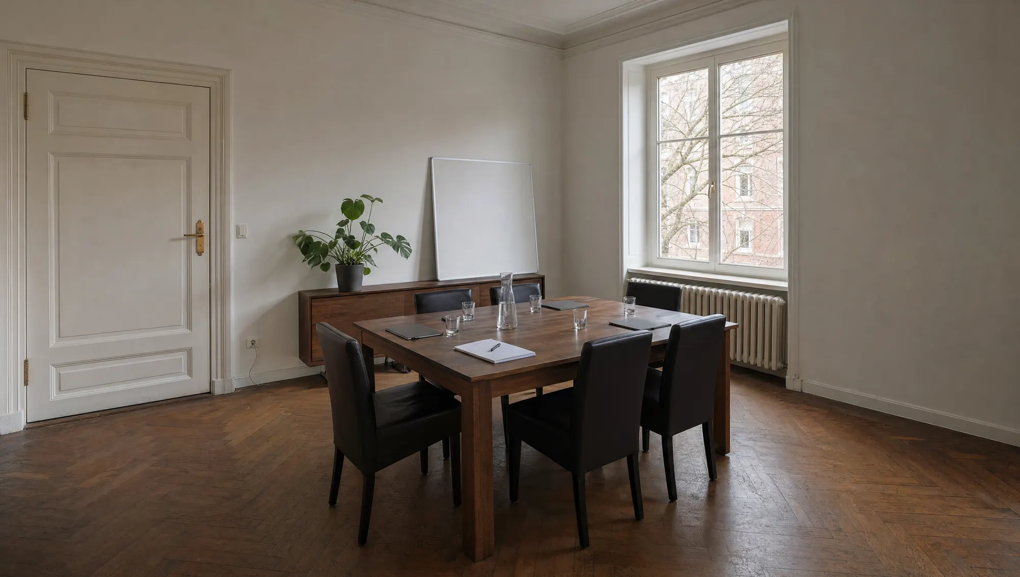 Besprechungsraum mit langem Eichentisch und dunklen Lederstühlen.