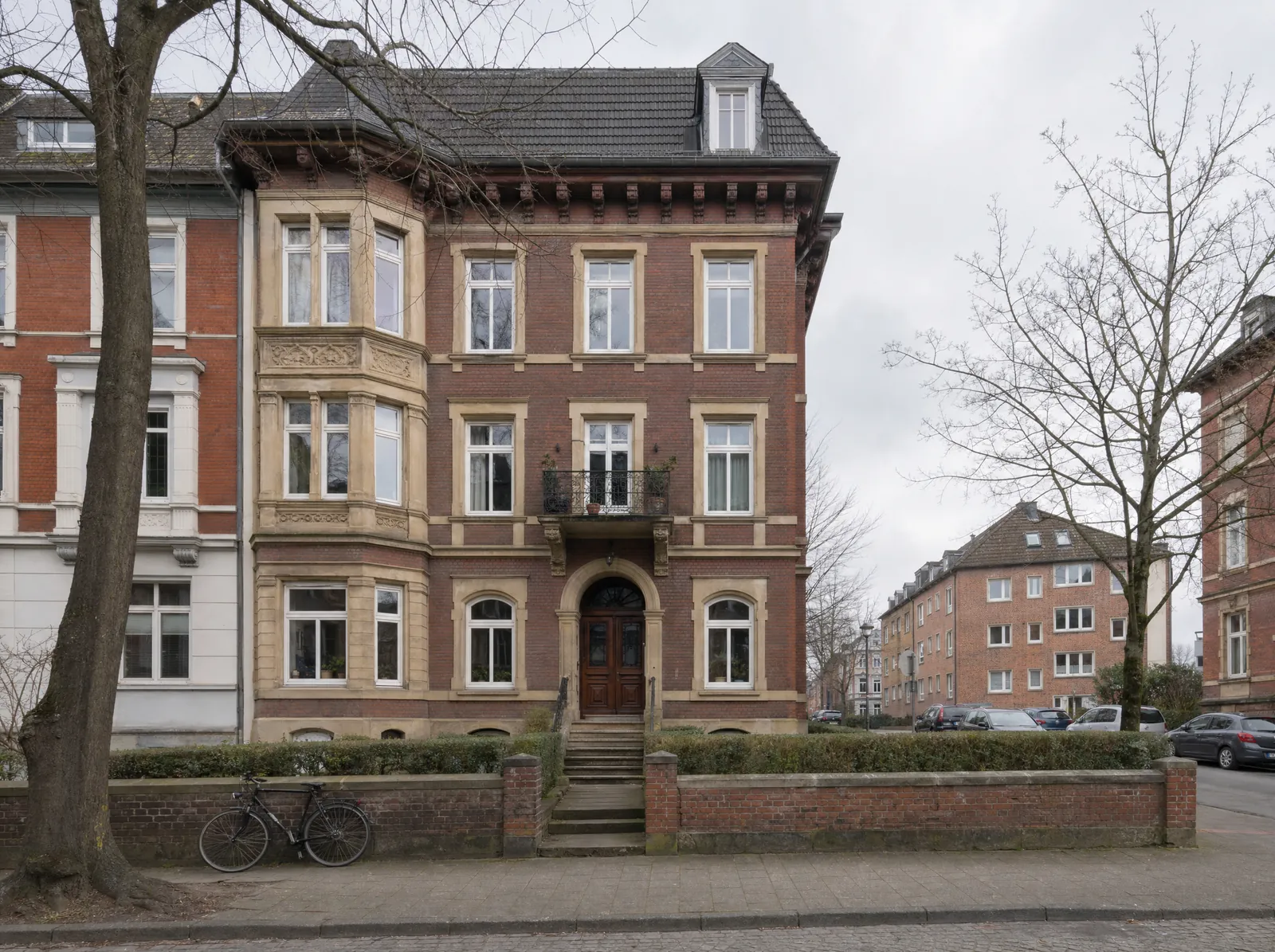 Gründerzeitliches Wohnhaus im Erphoviertel: vier Geschosse in dunkelrotem Klinker mit Sandsteingewänden, Erker, Balkon und weit auskragender Traufe.